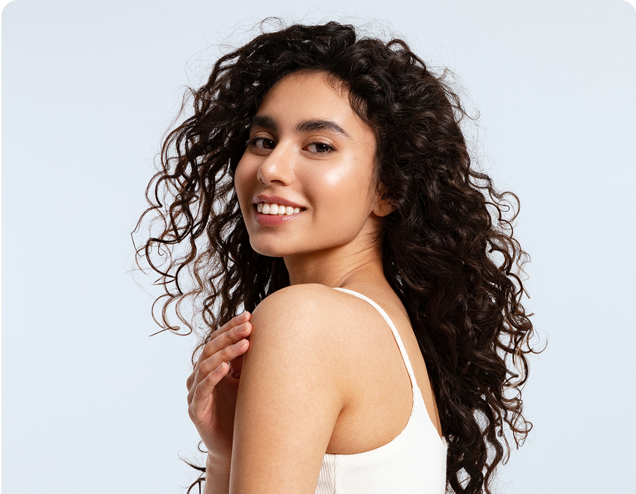 Woman with long, curly hair smiling on a light blue background